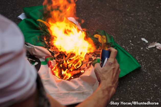  A protester using an aerosol can as a flamethrower to burn a Brazilian flag during the protests against the Olympic Opening Ceremony. 